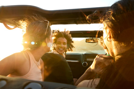 Group Of Laughing Female Friends Having Fun In Open Top Car On Road Trip