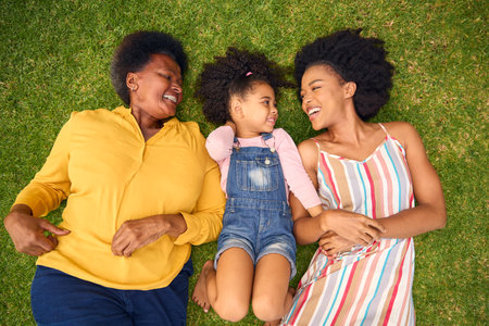 Overhead Shot Of Smiling Multi-Generation Female Family Lying On Grass In Garden Together
