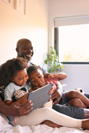 Grandfather And Grandchildren With Digital Tablet Pulling Funny Faces For Selfie At Homeの写真素材