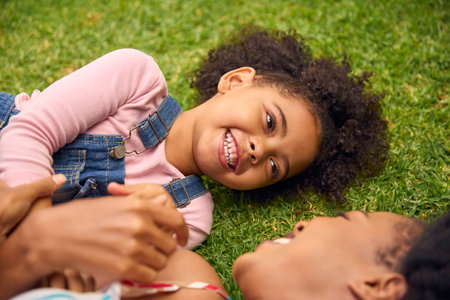 Close Up Of Smiling Mother And Daughter Lying On Grass In Garden Togetherの写真素材