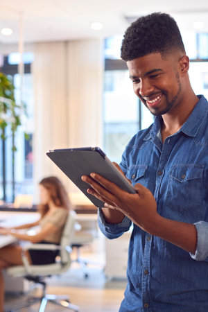 Young Smiling Businessman With Digital Tablet Standing And Working In Modern Office