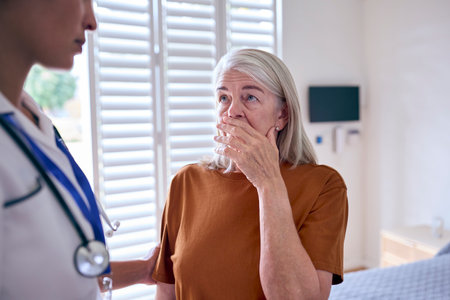 Female Nurse Wearing Uniform Giving Senior Woman Patient Bad News In Private Hospital Roomの写真素材