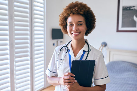 Portrait Of Smiling Female Nurse Wearing Uniform With Digital Tablet In Private Hospital Roomの写真素材