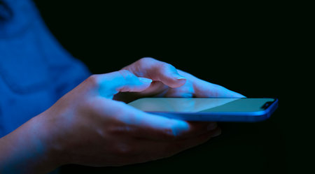 Close Up Of Woman Using Mobile Phone At Home At Night With Blue Lightingの写真素材