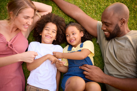 Overhead Shot Of Multi-Racial Family Lying On Grass Tickling Childrenの写真素材