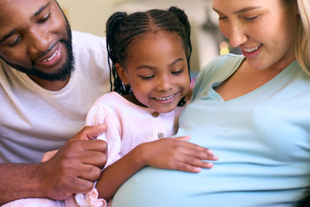 Family With Daughter Cuddling Pregnant Mother At Home Togetherの写真素材