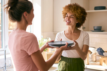 Two Female Friends Or Same Sex Couple Unpacking On Moving Day In New Homeの写真素材