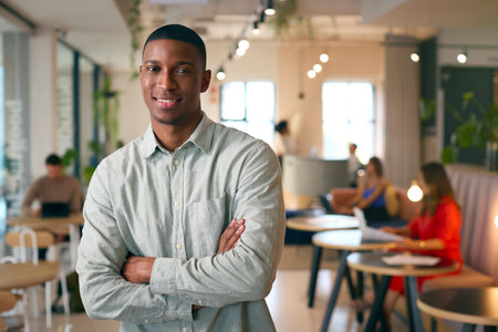 Portrait Of Smiling Businessman Standing In Busy Office