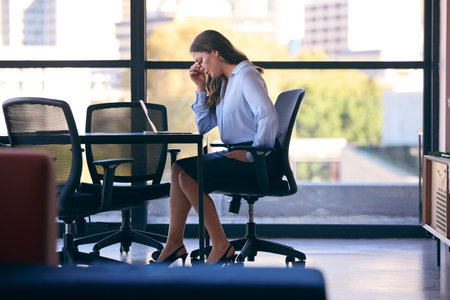 Stressed Mature Businesswoman Working On Laptop Sitting At Boardroom Tableの写真素材