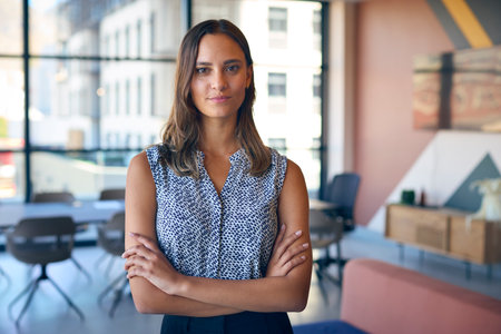 Portrait Of Young Businesswoman With Serious Expression Standing In Empty Officeの写真素材