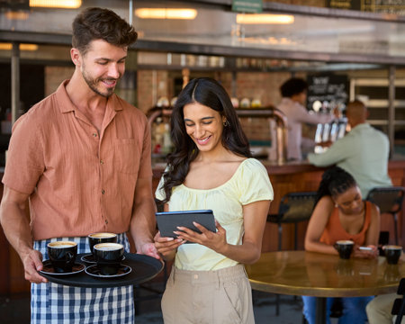 Female Manager With Digital Tablet And Waiter Working In Restaurant Or Coffee Shopの写真素材