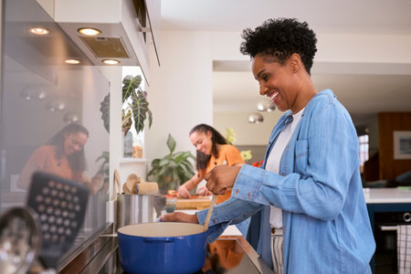 Mother With Teenage Daughter Helping To Prepare Meal At Home In Kitchen Togetherの写真素材