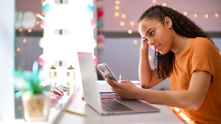 Stressed Teenage Girl At Home In Bedroom Being Bullied Online Looking At Mobile Phone