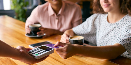 Woman In Coffee Shop Paying Bill With Contactless Card Paymentの写真素材