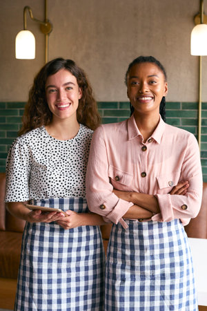 Portrait Of Two Smiling Female Owners Or Staff Working In Cafe Or Coffee Shopの写真素材