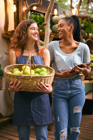 Two Women With Basket Of Lemons And Digital Tablet Working At Fruit And Vegetable Stall In Marketの写真素材