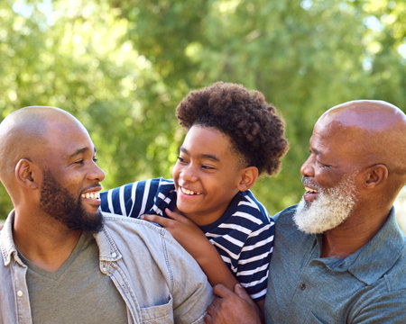 Multi-Generation Male Family Having Fun Playing Outdoors In Garden Park Or Countrysideの写真素材