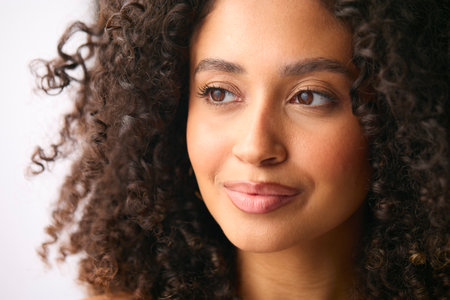 Close Up Studio Portrait Of Smiling Natural Woman Standing Against Neutral Backgroundの写真素材