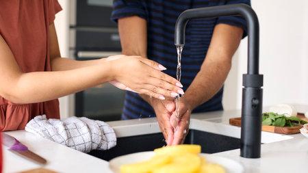 Close Up Of Couple At Home Washing Hands Before Preparing Meal In Kitchenの写真素材