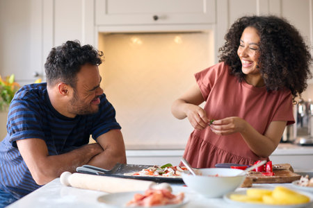 Couple At Home With Man With Down Syndrome And Woman Putting Toppings On Pizza In Kitchen Togetherの写真素材