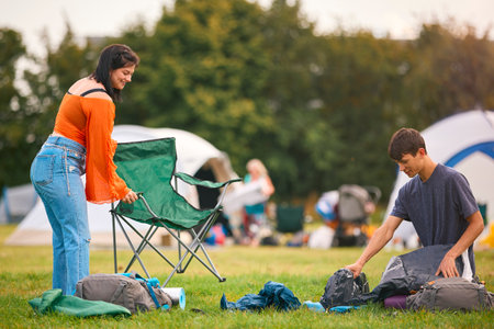 Young Couple Setting Up Tent At Summer Music Festival Unpacking Camping Equipment