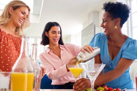 Three Mature Female Friends At Home Having Fun Mixing Cocktails Togetherの写真素材