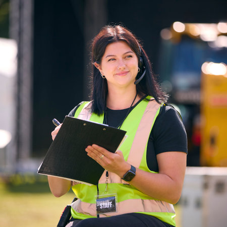 Female Production Worker Setting Up Outdoor Stage For Music Festival Or Concert