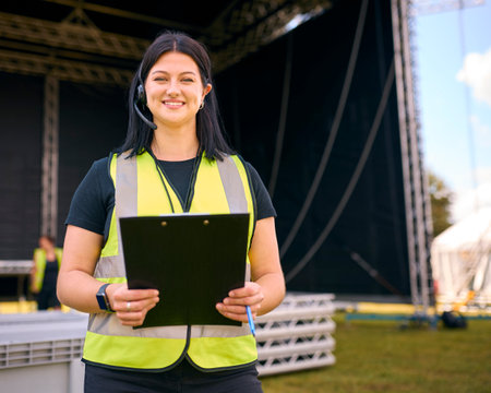 Portrait Of Female Production Worker Setting Up Outdoor Stage For Music Festival Or Concertの写真素材
