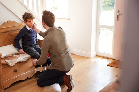 Single Father At Home Getting Son Wearing Uniform Ready For First Day Of Schoolの写真素材