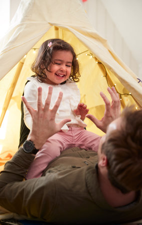 Single Father Playing With Daughter In Den In Bedroom At Home