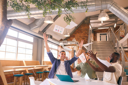 Businessmen Meeting In Modern Office Sitting Around Table Celebrating Throwing Documents In The Air