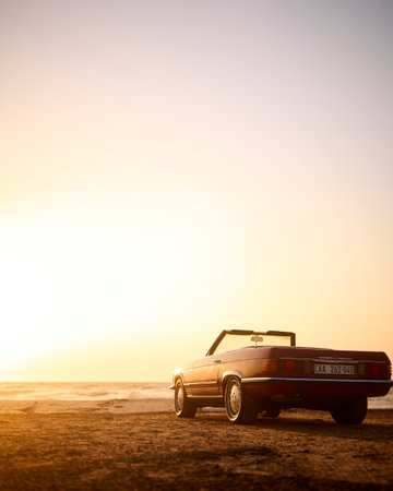 Classic Convertible Sports Car On Shoreline Of Beach At Sunrise