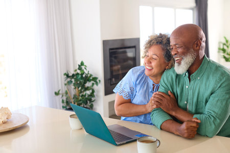 Mature Couple At Home With Laptop Making Video Call To Family Or Friends