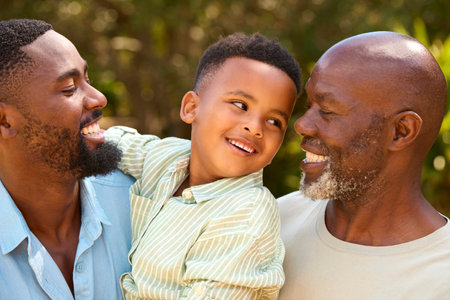 Loving Three Generation Male Family Laughing And Hugging Outdoors In Countrysideの写真素材