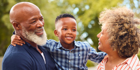 Loving Grandparents Hugging Grandson Outdoors In Countryside Or Garden