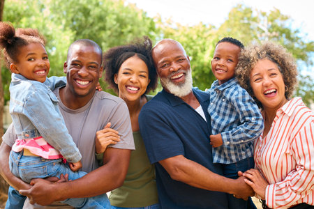 Portrait Of Three Generation Family Outdoors Laughing And Holding Grandchildren In Countrysideの写真素材
