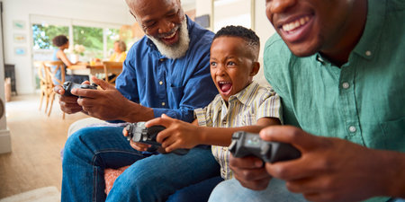 Grandfather With Father And Grandson Playing Computer Game At Home With Family In Backgroundの写真素材