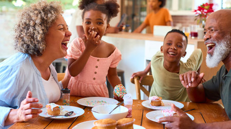 Grandparents With Grandchildren Indoors At Home Decorating Cakes Together With Family In Backgroundの写真素材