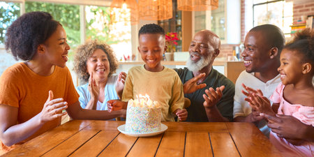 Multi-Generation Family Celebrating Grandson's Birthday At Home Blowing Out Candles On Cakeの写真素材