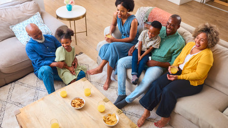 Multi-Generation Family Sitting In Lounge At Home Watching TV Togetherの写真素材