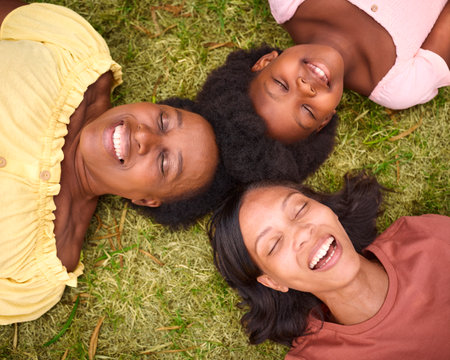 Looking Down On Three Generation Female Family With Eyes Closed Laughing And Lying On Grass Outdoorsの写真素材