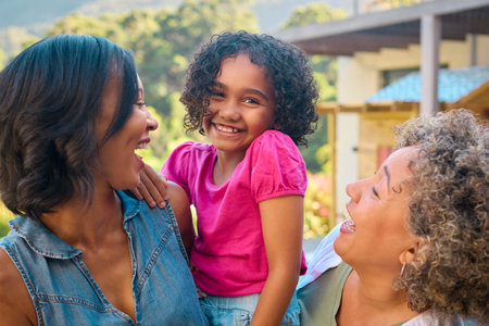 Portrait Of Three Generation Female Family Laughing And Smiling Standing Outdoors In Countrysideの写真素材