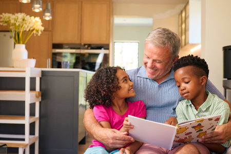 Multi Racial Family With Grandfather Looking After Grandchildren At Home Reading A Story Together
