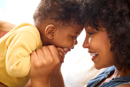 Close Up Of Mother And Baby Daughter Cuddling On Sofa At Home Togetherの写真素材