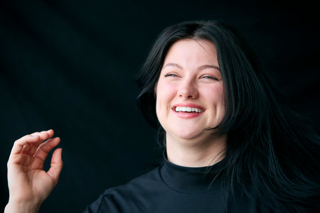 Studio Shot Of Young Woman Laughing And Smiling With Happy Expression Against Black Backgroundの写真素材
