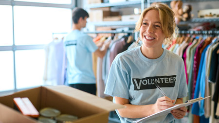 Female Charity Worker Receiving Food Donations From Member Of Public At Foodbankの写真素材