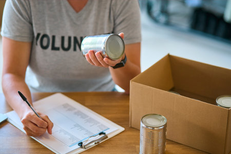 Close Up Of Female Charity Worker Checking Food Donations At Foodbank Or Thrift Storeの写真素材