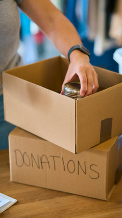 Close Up Of Female Charity Volunteer Working At Food Bank Unpacking Donationsの写真素材