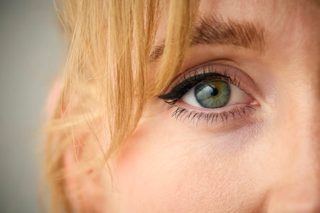 Close Up Studio Shot Of Woman's Eye Looking At Camera Against Plain Studio Backgroundの写真素材