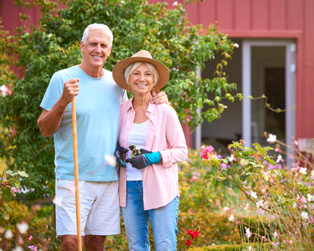 Portrait Of Loving Senior Retired Couple Outdoors At Home Working In Garden Togetherの写真素材